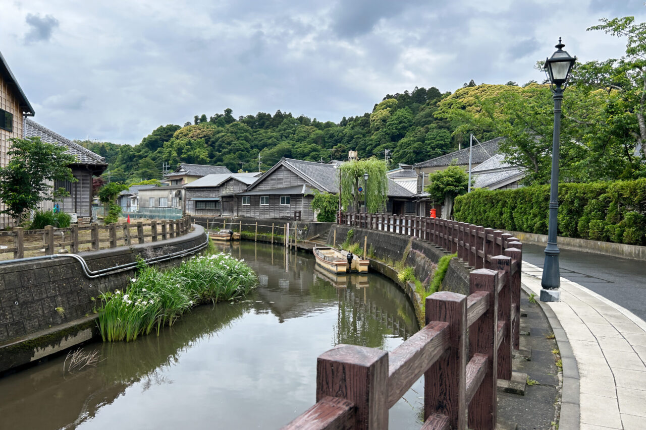 Wooden buildings and small boats along a quiet waterway in Sawara