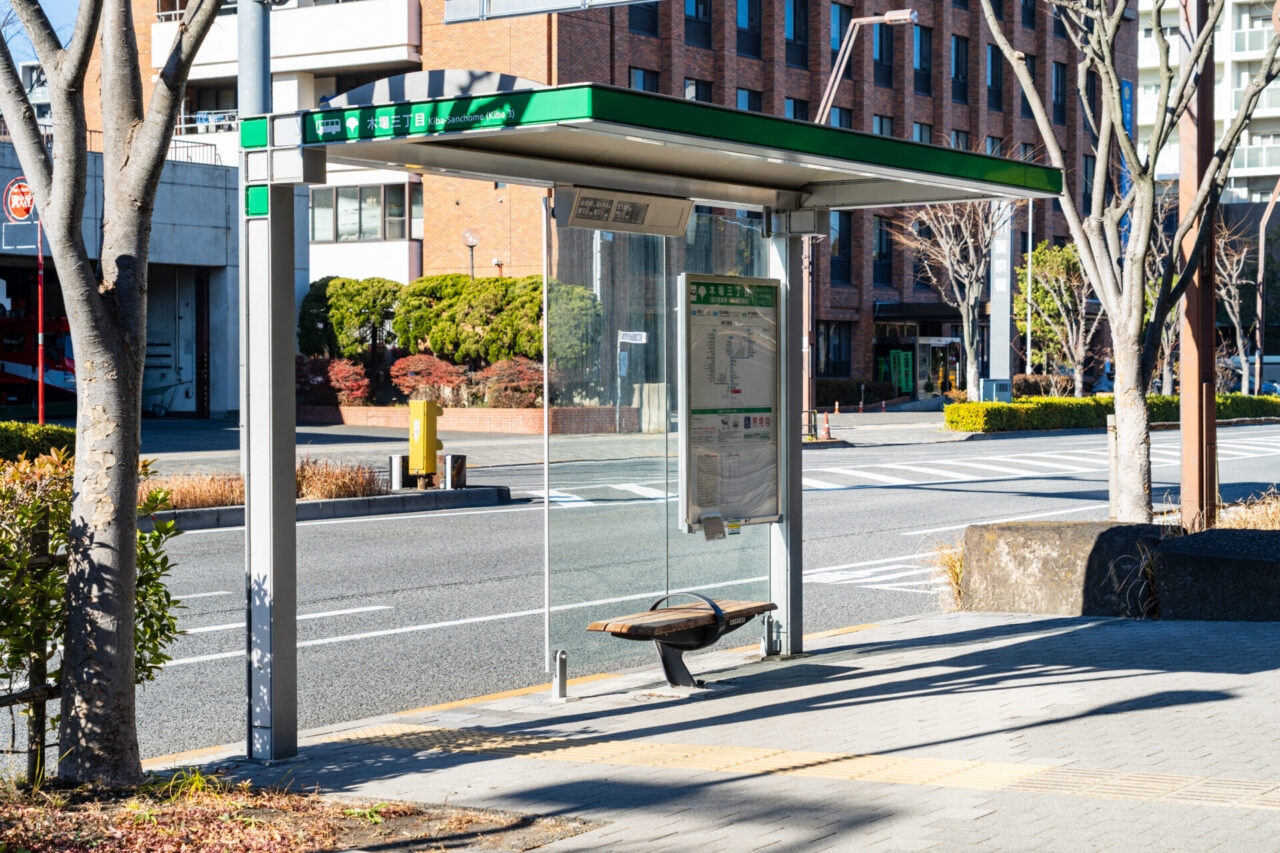 Covered local bus stop with route information and a bench in Japan