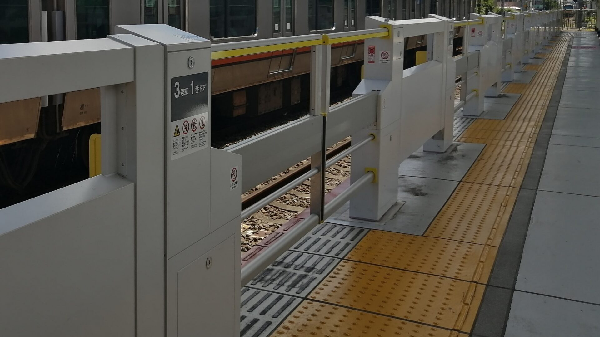 Yellow tactile paving beside platform screen doors at a railway station in Japan